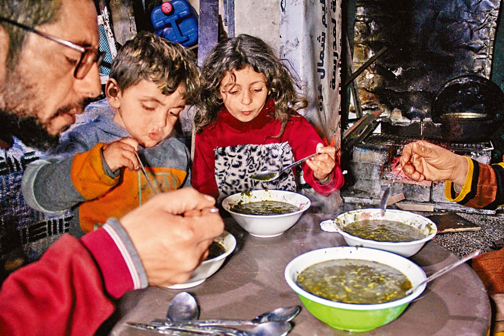 在加沙北部贾巴利亚，一个家庭在吃野生植物霍比扎果腹。