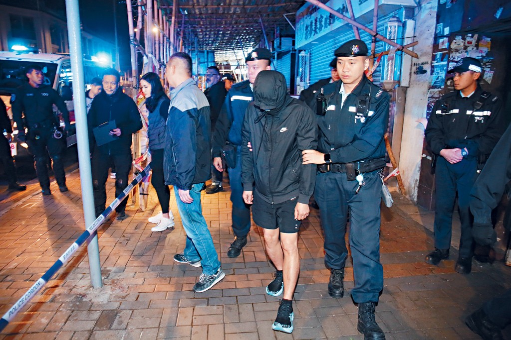 涉嫌「管有爆竹煙花」被捕的男子由警員押走。