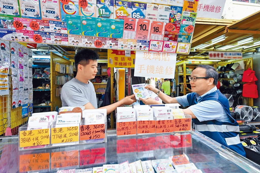通訊辦昨日在鴨寮街一帶進行突擊市場巡查，職員（右）並派發傳單提醒商戶切勿售賣來歷不明或聲稱已完成登記的電話儲值卡。
