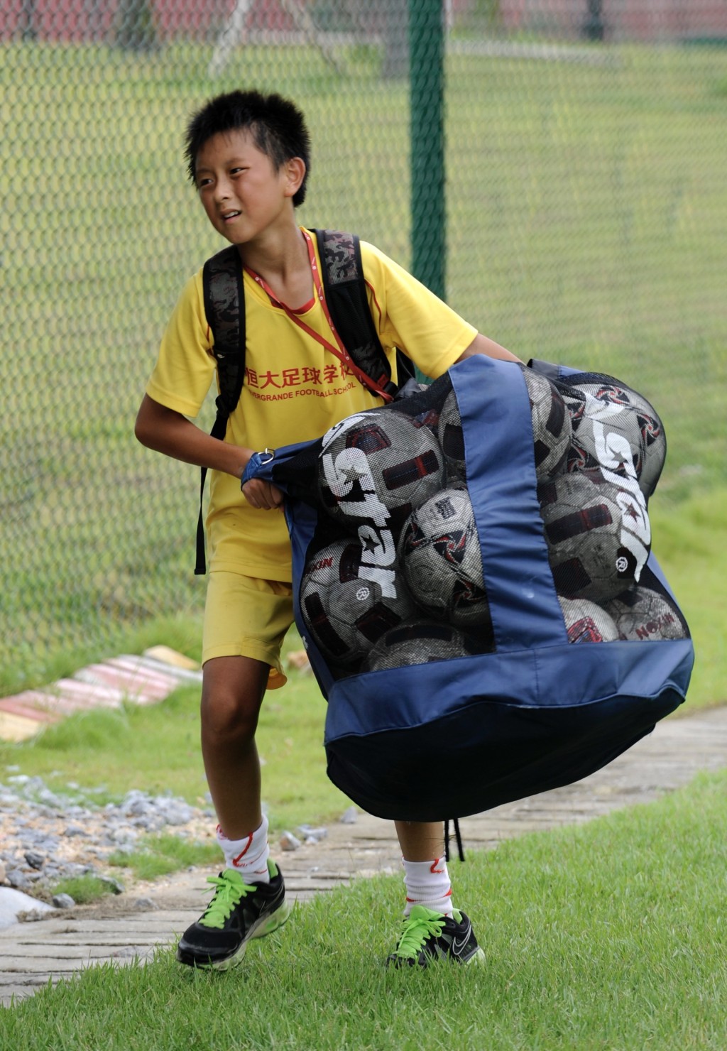 一名小球員在訓練結束後搬運一袋足球。 新華社資料圖