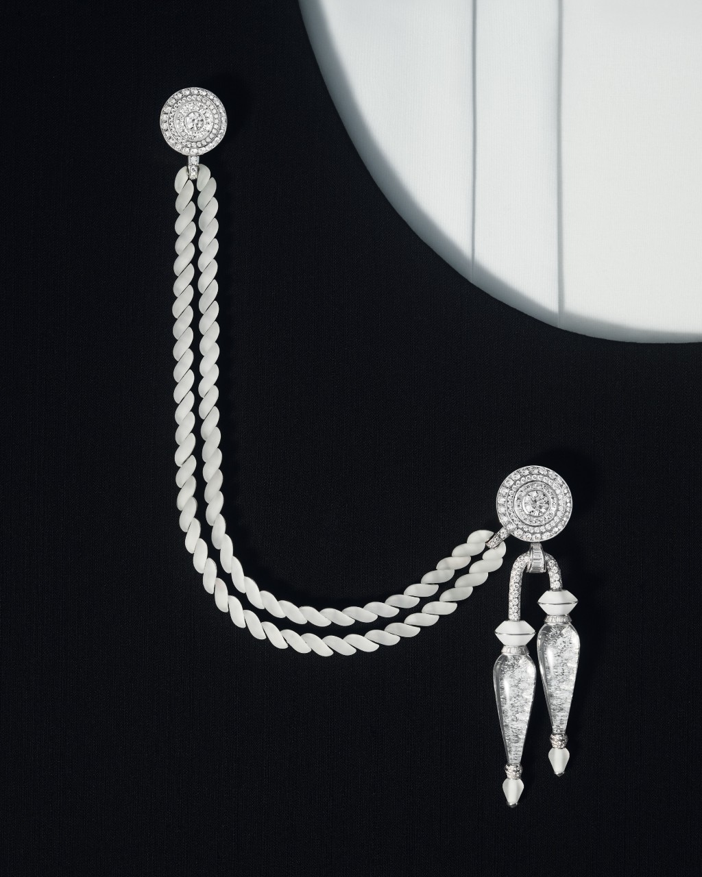 Aiguillette织绳穗饰，以白金、水晶和钻石交织而成，镶嵌一颗重2.11卡圆形钻石，佩戴方式多变，可拆分成两枚胸针及一条磨砂水晶手链。