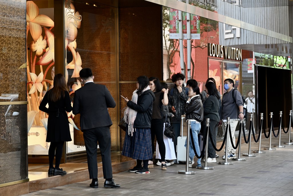 不少遊客排隊入名店購物。
