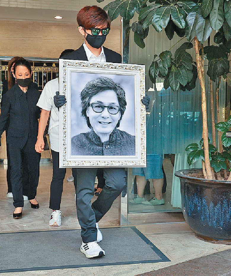 ■大仔捧着爸爸的遺照離開靈堂。 ■大仔捧着爸爸的遺照離開靈堂。