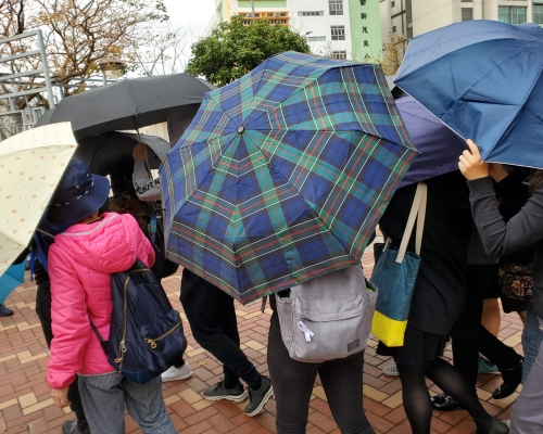 有市民以傘陣掩護被告離開。 葉君怡攝
