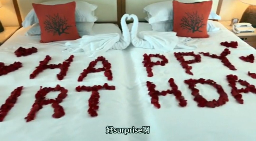 红玫瑰花瓣布置嘅双人床。