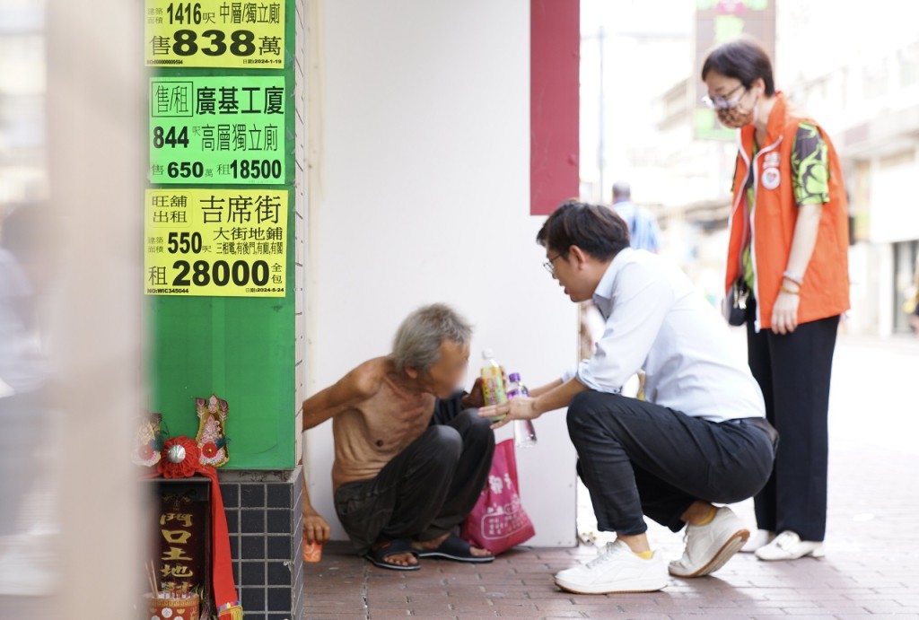 中西區區議員楊開永(中)與關愛隊成員在卑路乍街探望用渠邊污水流臉的露宿者。(許文光攝)