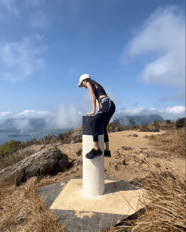 陈凯琳登上山顶时，未见喘气更成功一跃而上坐在山顶标竿的圆柱。