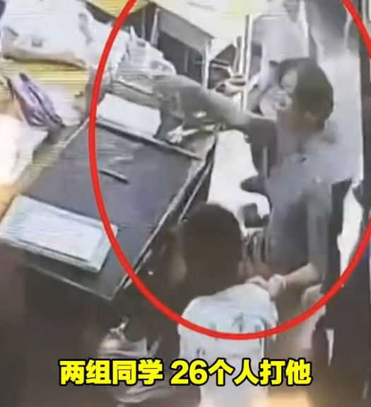 监控片段显示，坐著的女教师捉著男生，要全班26人轮流拍打该男生。