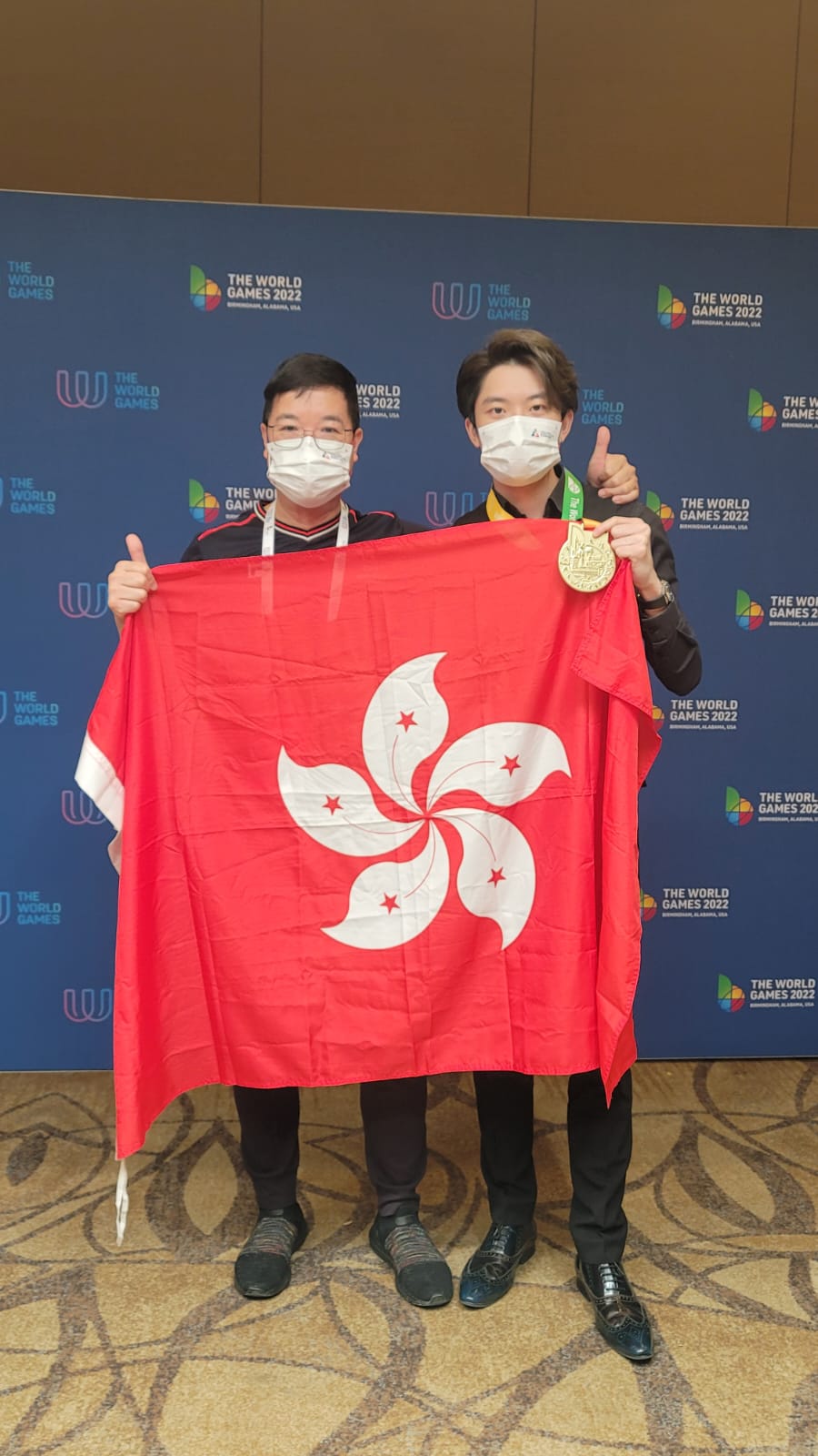 黃德華教練與張家瑋高舉區旗。 香港桌球總會圖片