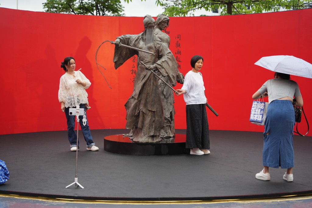 游客到中环金庸雕塑展拍照。