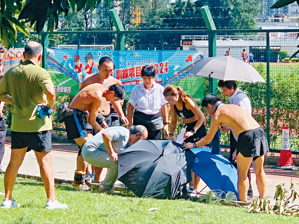 死者在公園跑步徑暈倒,多名途人上前協助,有人打開雨傘為他遮蔭。