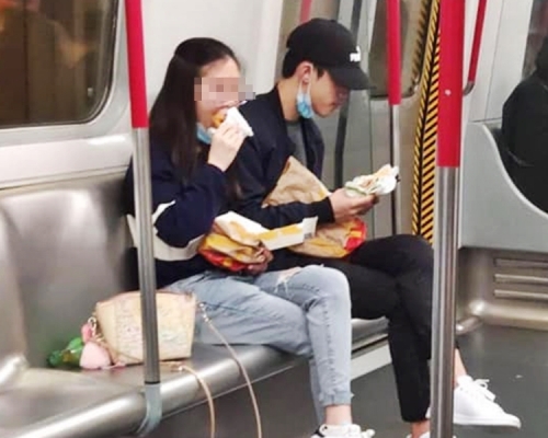 一對男女坐在港鐵車廂內,公然將口罩拉低至下巴位置,吃快餐店外賣。「將軍澳討論區」Facebook圖片