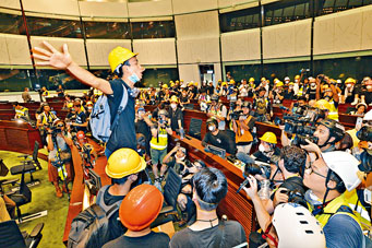 ■在立法会会议厅内拉低口罩，读出示威者诉求的梁继平。