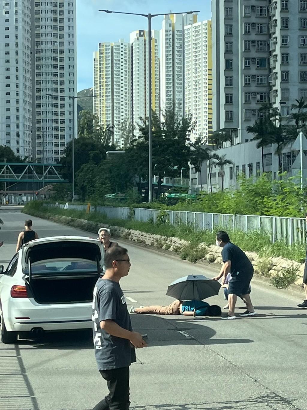 男子捱撞后倒卧地上，有热心途人见状上前打开雨伞，为事主遮挡猛烈阳光。网上图片