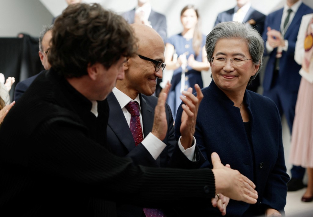 Google聯合創始人布林與AMD首席執行官蘇姿丰握手，微軟首席執行官納德拉坐在他們中間。路透社