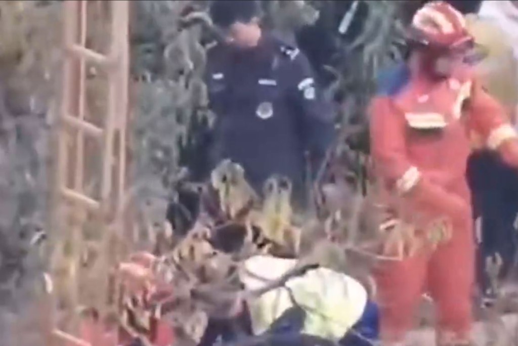救援人员在现场将落井的2名成人救出。影片截图