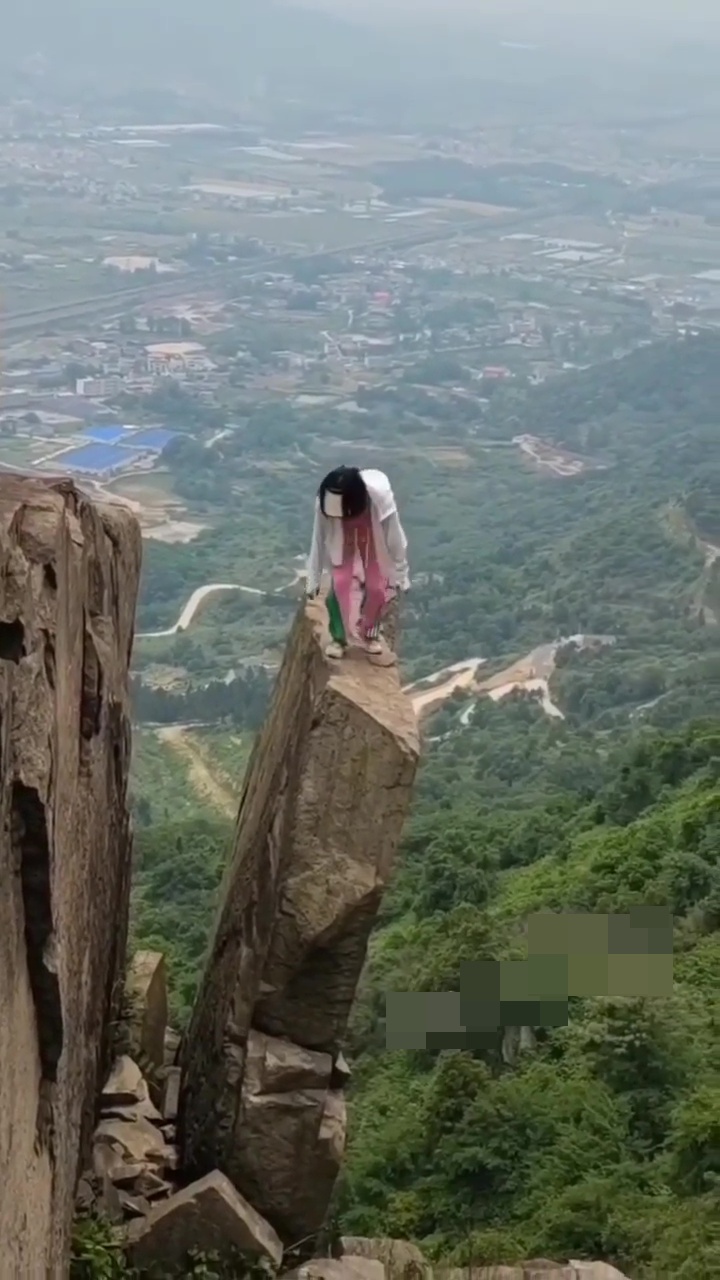 女子準備再爬石罅返回懸崖邊。網上截圖