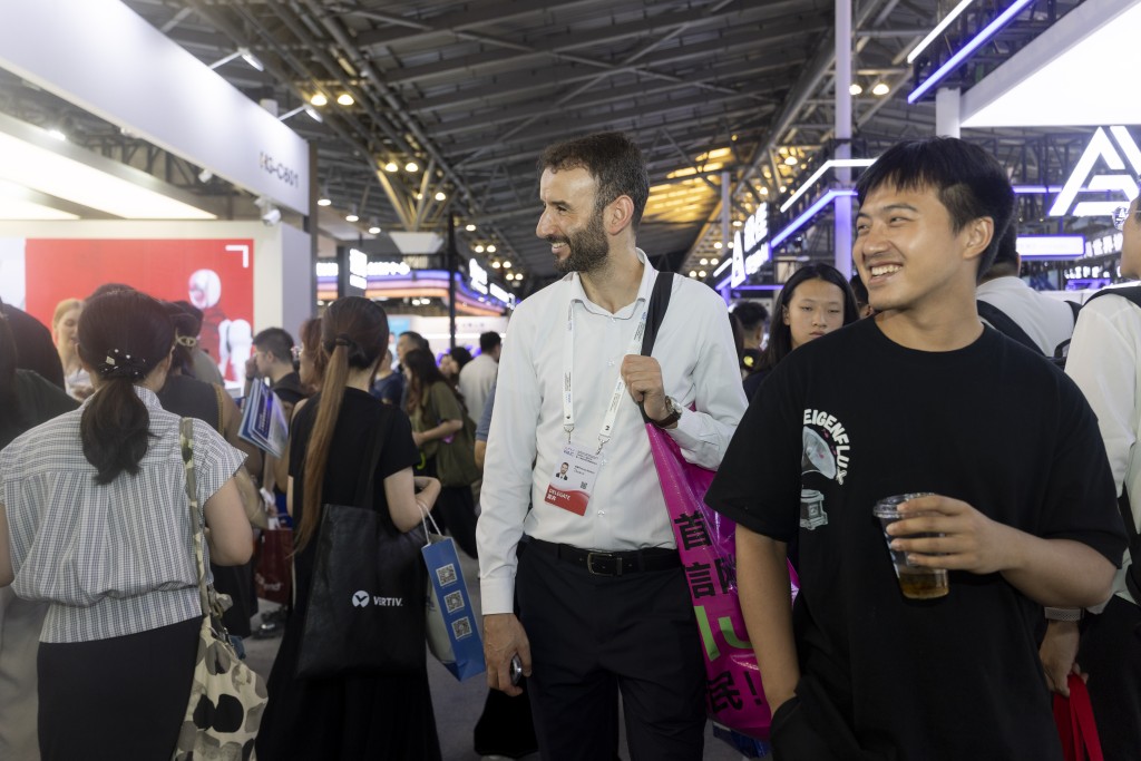 伯涵峥（左）在2026世界人工智能大会展馆内和青年创业者交流。 新华社