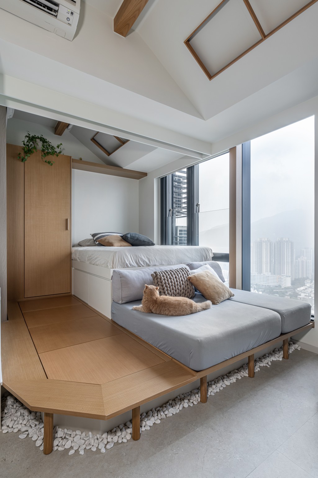 設計師想到將睡房的地台擴大至客廳，訂造一張淺灰色的咕𠱸椅取代傳統梳化