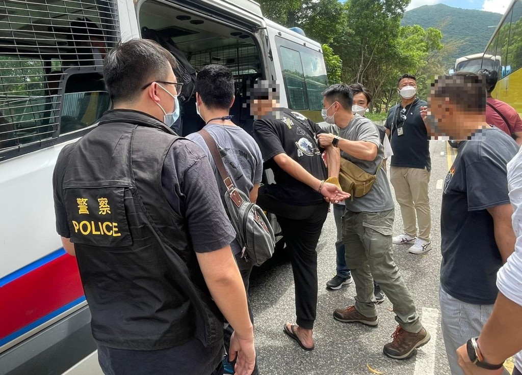 警方搗破懷疑非法牌九賭檔,涉案人士被押上警車。