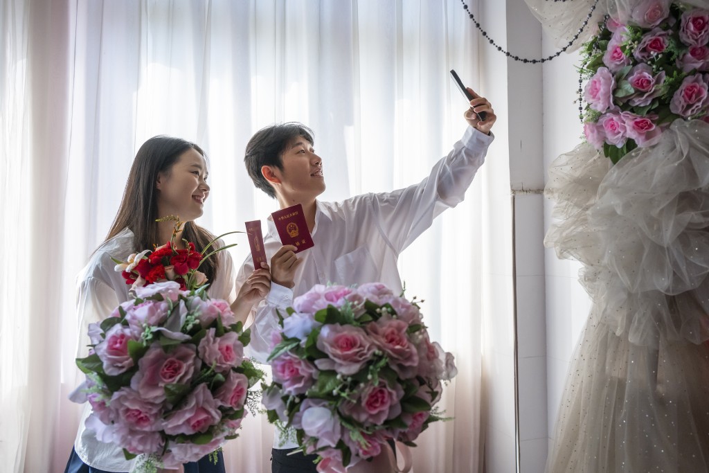 一對新人領取結婚證後拍照留念。 新華社