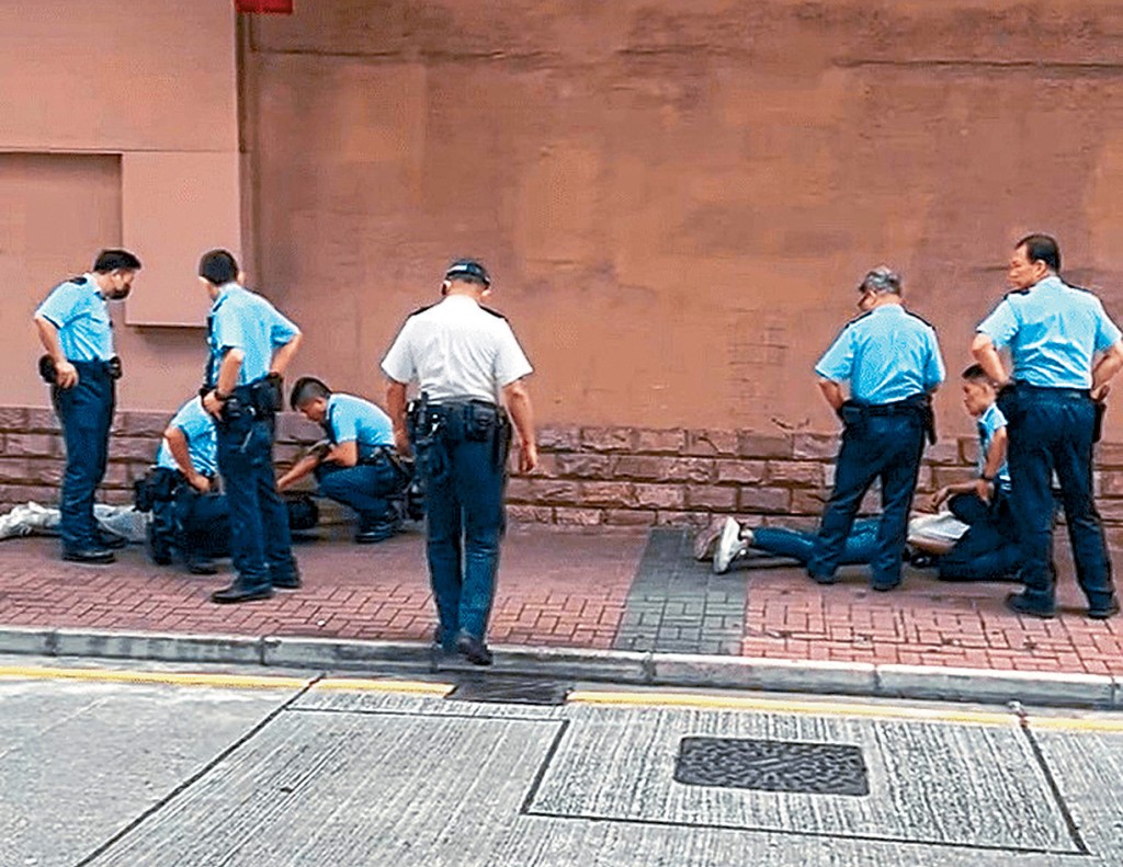 兩名男子遭警員制服後按在地上。
