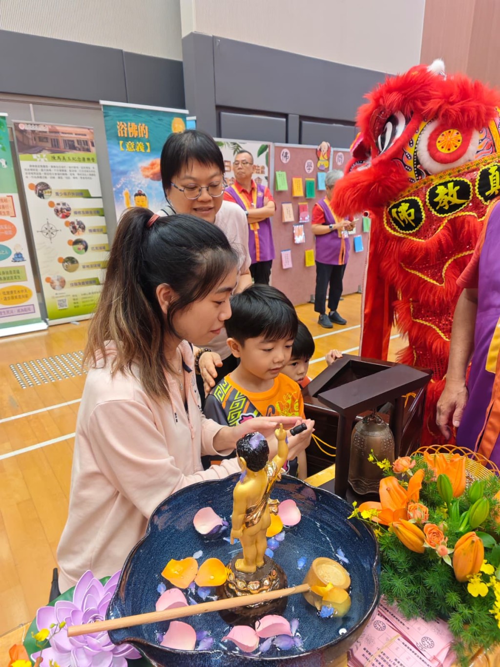 有家長帶同子女一同參與浴佛，為佛像頭頂淋水及跪拜。