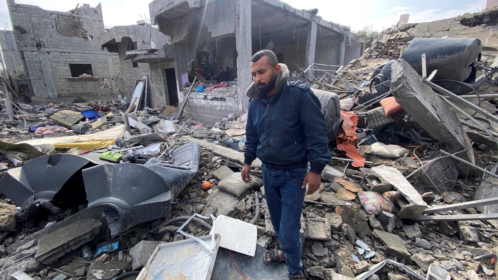 一名巴勒斯坦男子在空袭中痛失妻子及4个孩子，无奈地站在瓦砾堆中。 路透社