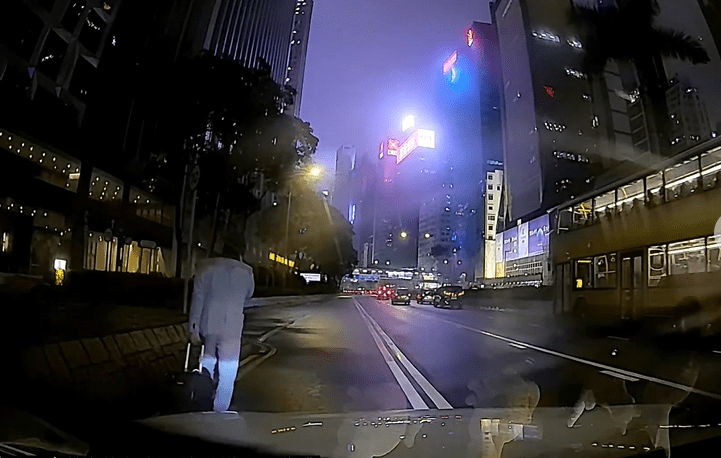 即使車頭燈亮起，拖篋男仍無視危險，完全沒有回頭留意行車狀況。fb 車cam L（香港群組）Ting Yu Cheung