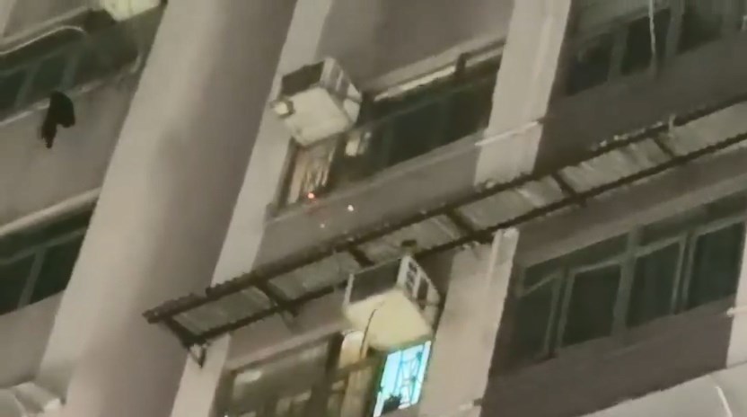 一名男子將已點燃的紙張放在窗邊，火屑隨風四散飄盪，散落街道。fb「香港交通及突發事故報料區」Michelle Lam片段截圖