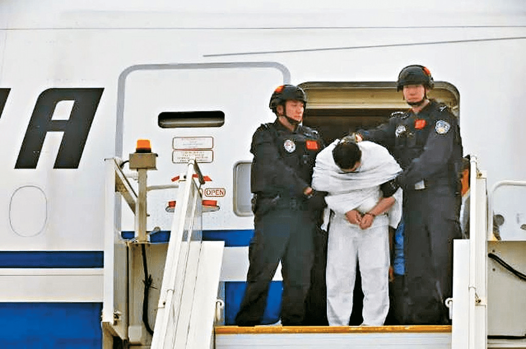 嫌疑人劉某文在警方押送下走出機艙。 新華社