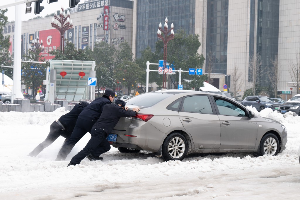 湖南警察在雪中推車。