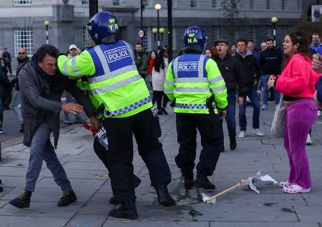 倫敦一名反抗議者試圖從女示威者手中搶走撐巴人標語牌，警員見狀出手制止。路透社