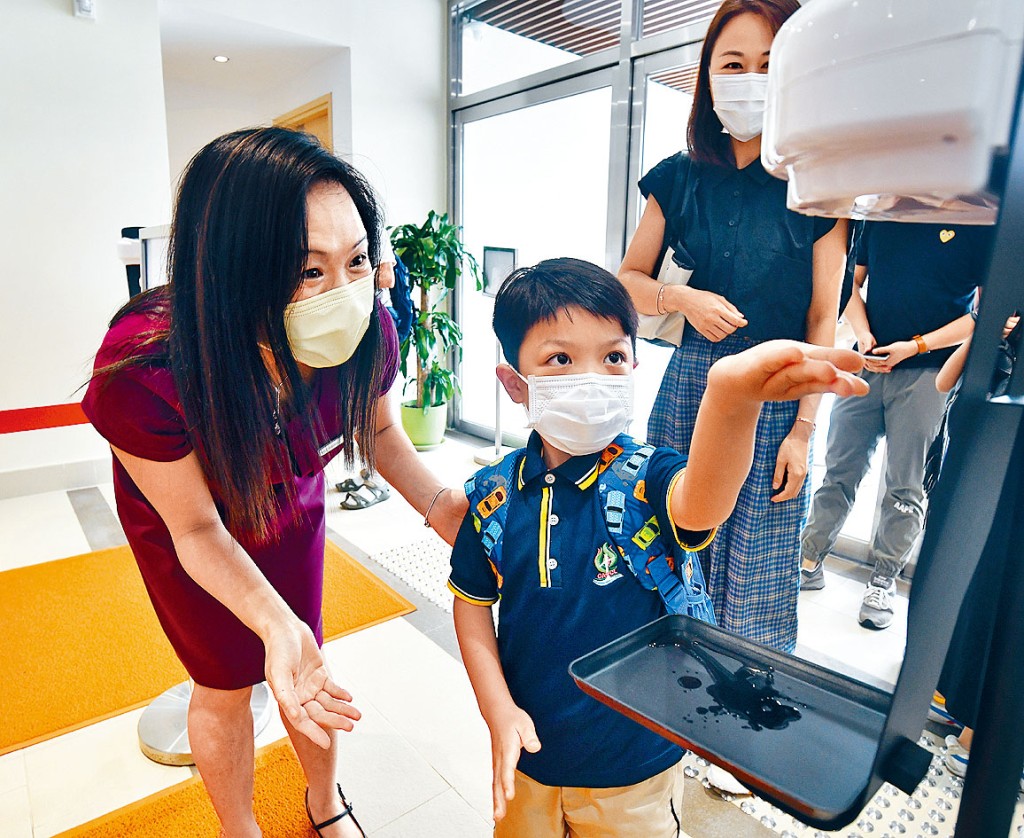 刘平斋国际学校昨举行小一迎新日，校长许陈干华（左）在校门迎接返校学生，并教他们如何消毒双手。