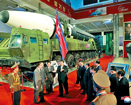 金正恩於武器展場上與官員交談。