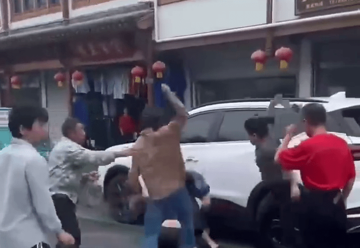 橫間T-恤男被一人推至車旁，其他人則不停施暴。