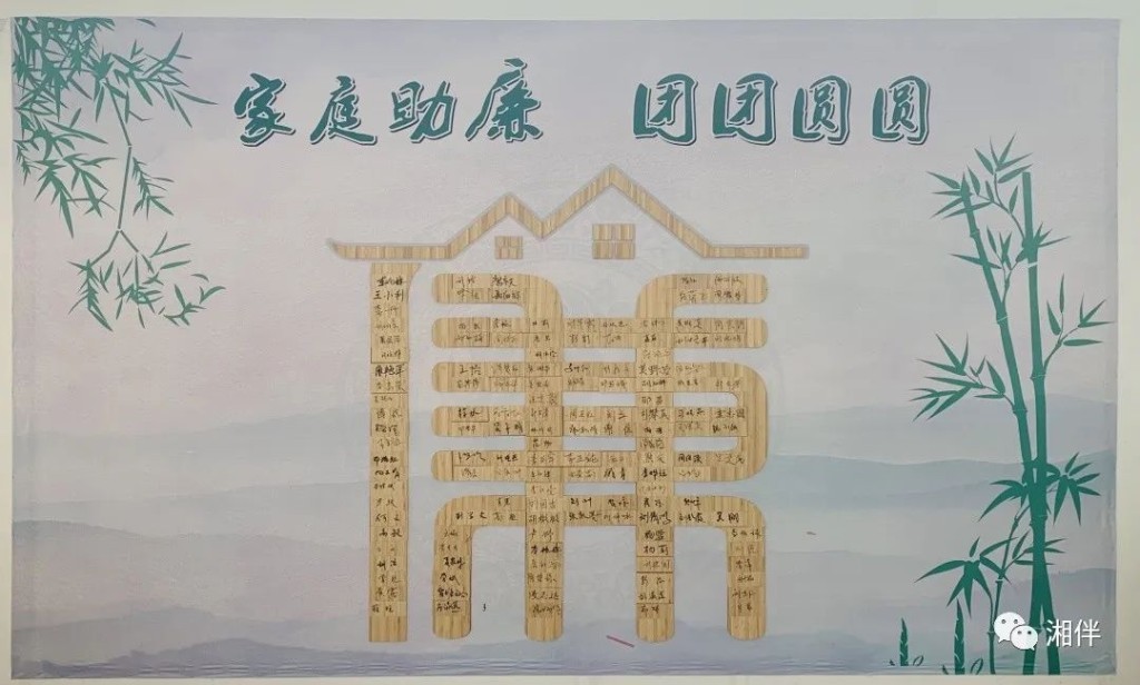 桃江县一把手配偶在竹片上签名字后将其镶入墙上的廉字中。