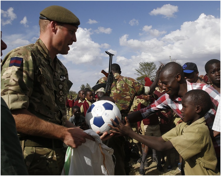 威廉王子到访一间学校和小学生踢波。AP 