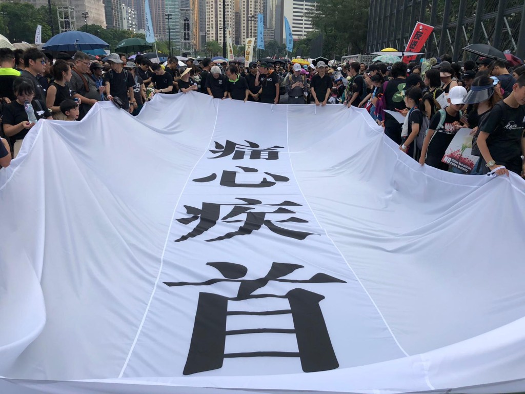 遊行隊頭拉起「痛心疾首」白底黑字大橫幅在維園出發。