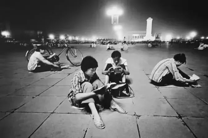 開革開放後，坐在天安門廣場借光讀書準備高考的年輕人。 （黑白圖片）