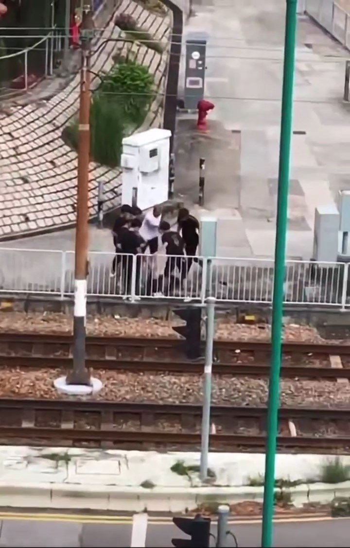 一批身穿短袖衫的童黨在行人路上，對一名黑衣青年拳打腳踢。網上片段截圖