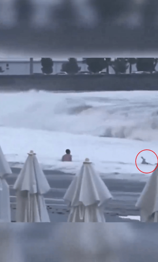 一陣浪退，見到男子被沖到較近岸的地方，但女子卻留在水裡，然後又一個巨浪撲來，這次直接把女子捲走。