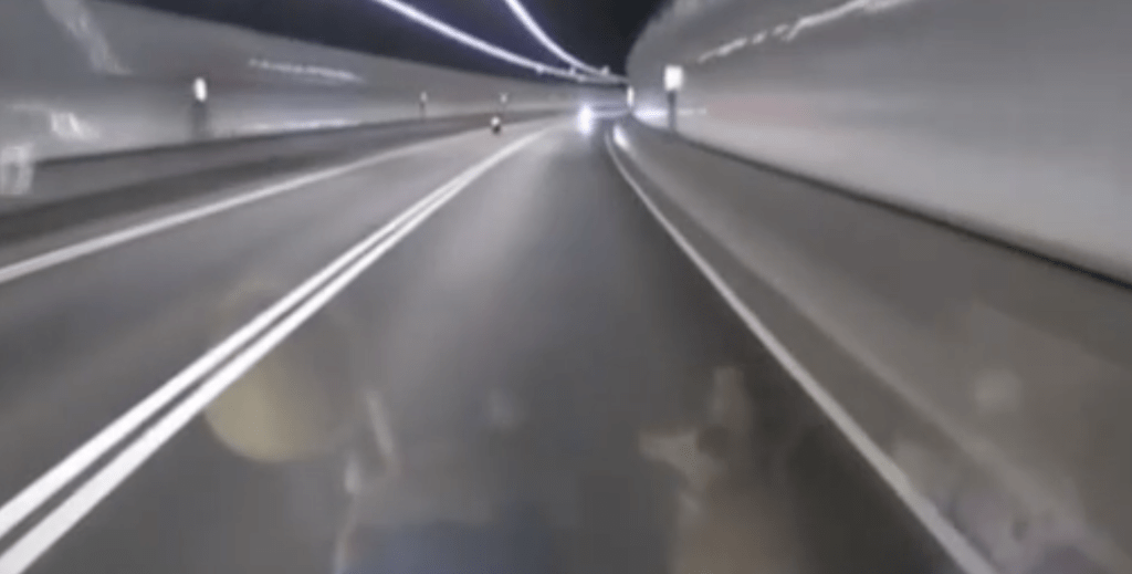 其中一段影片拍於昨晚11時45分，片主沿尖山隧道快線往九龍方向行駛，隔離中線前方則有一輛電單車開着，突然一輛白色私家車在快線逆線出現。