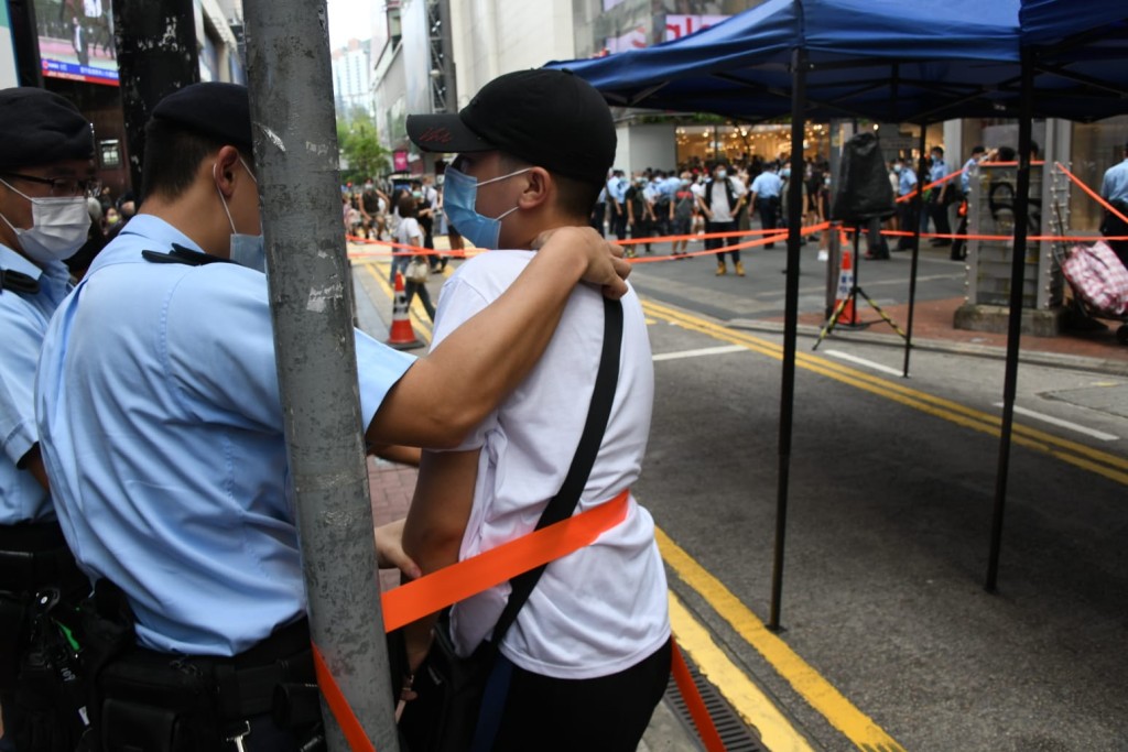 一名年青男子被警員帶上警車。