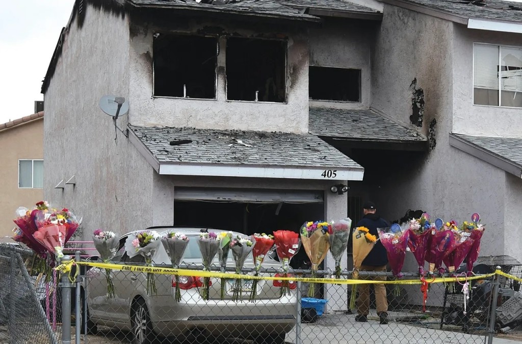 民众在火灾现场献花悼念5名死者。美联社