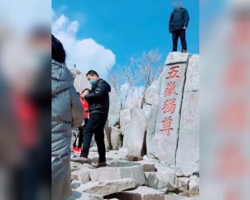 游客站在泰山「五岳独尊」石刻上拍照，公安已立案调查。(网图)