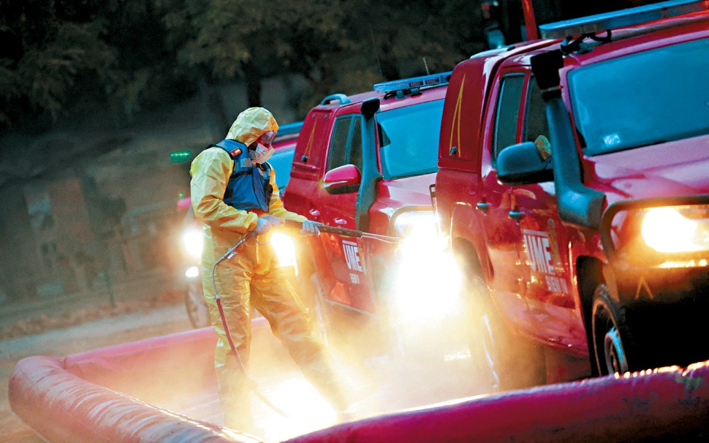 西班牙參與應對豬瘟的緊急軍事單位士兵，在巴塞隆拿郊區向離開限制區的車輛噴灑消毒劑。