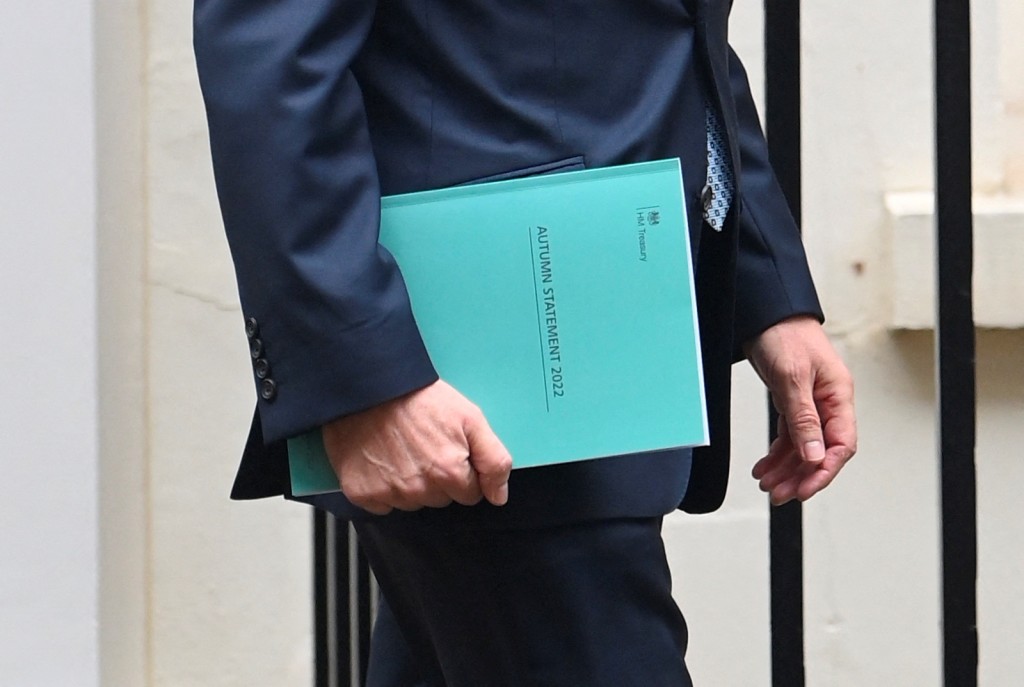 英國財相侯俊偉周四在國會，公布首相辛偉誠上任後首份財政預算案，他手持的預算案是綠色封面。路透