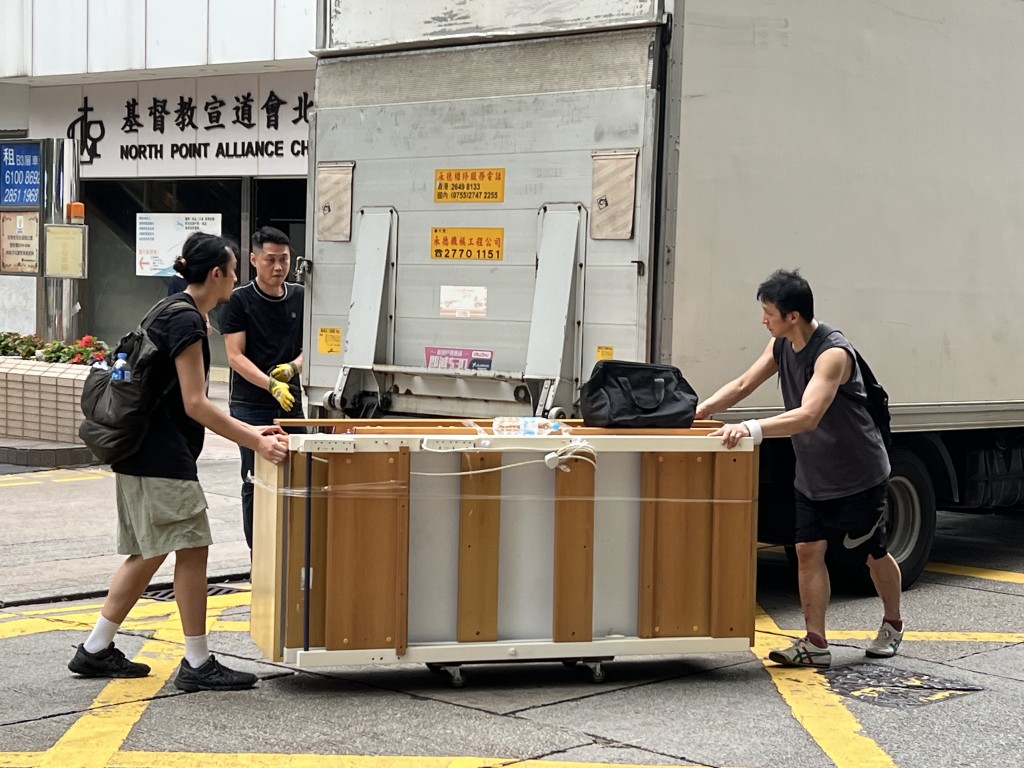 两名搬运义工翁先生(右)及阿达(左一)再将床架搬入车运送至柴湾新居。