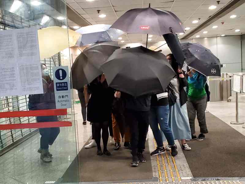 被告(黃色褲)在傘陣掩護下離開法院。張旭珊